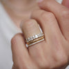Woman wearing a trio set of diamond mosaic engagement ring with cross cross engraved wedding band, and pave diamond ring.