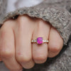 This exquisite ring showcases a rare unheated cushion cut opalescent ruby-colored sapphire, surrounded by eight dazzling diamonds in round, carré, and baguette cuts, offering a perfect blend of vibrant color and sparkling brilliance in a luxurious design.