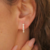 Woman wearing a pair of vintage diamond hoop earrings with six asscher cut diamonds and four round diamonds set in 18k yellow gold.
