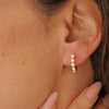 Woman wearing a pair of vintage diamond hoop earrings with six asscher cut diamonds and four round diamonds set in 18k yellow gold.