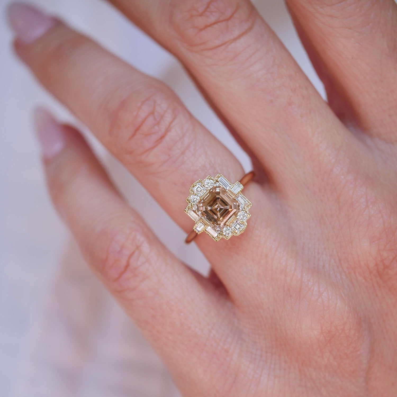 Close-up of a hand wearing a ring with white diamond and a champagne asscher center