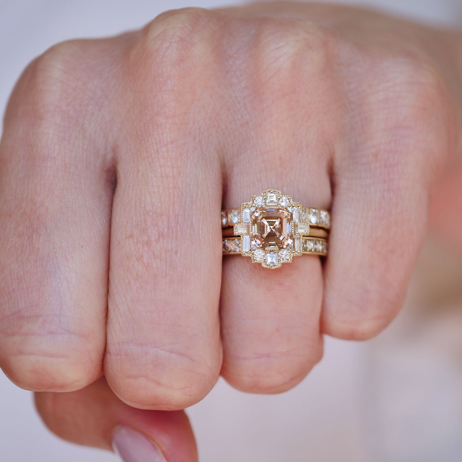 Gold ring with diamond on a person's finger against a neutral background