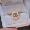 Gold ring with a central unique champagne diamond and surrounding white diamonds.