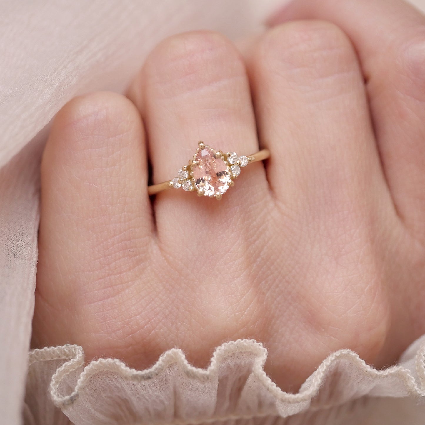 woman wearing 14k yellow gold pear sapphire and round diamond engagement ring