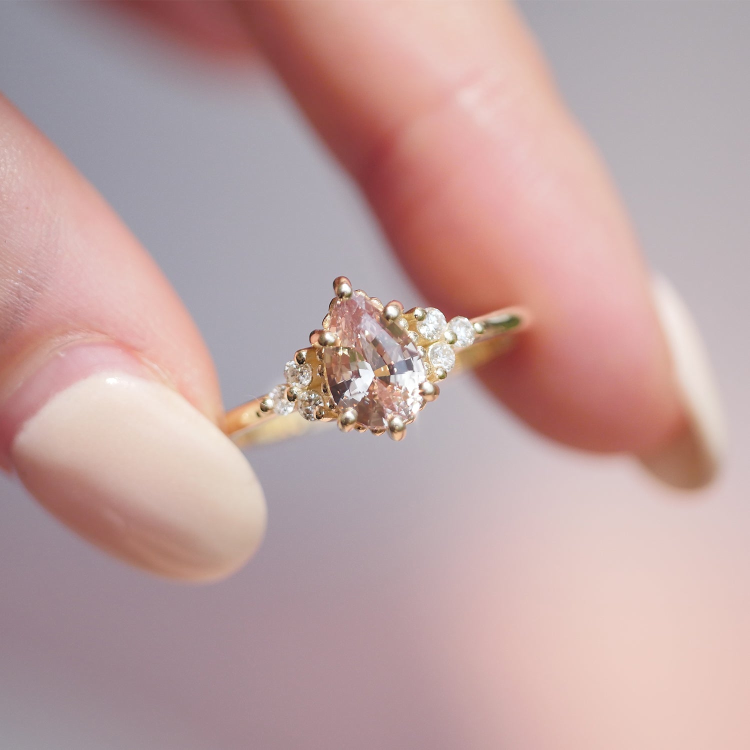 woman holding 14k yellow gold pear sapphire and round diamond fine jewelry ring