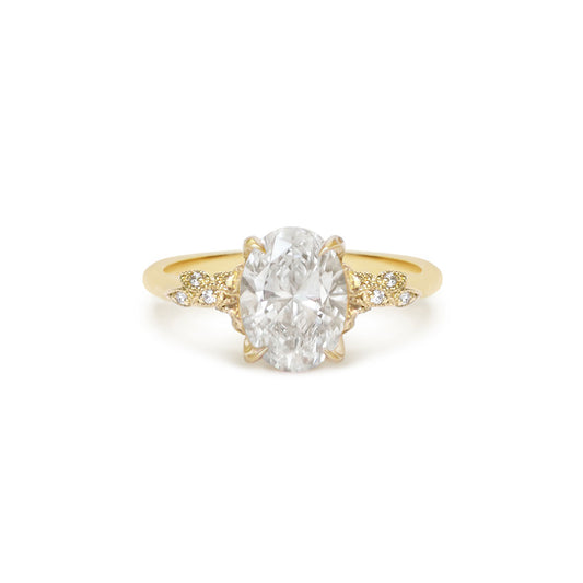 An oval-shaped diamond ring with smaller round diamonds set in a 14k yellow gold band