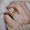 Close-up of a hand wearing a sapphire solitaire engagement ring with nature inspired diamond band