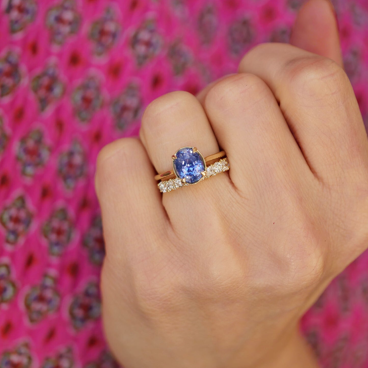 woman wearing oval shaped blue sapphire solitaire and a diamond confetti diamond band