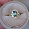 Gold ring with a green gemstone on a beige cushion