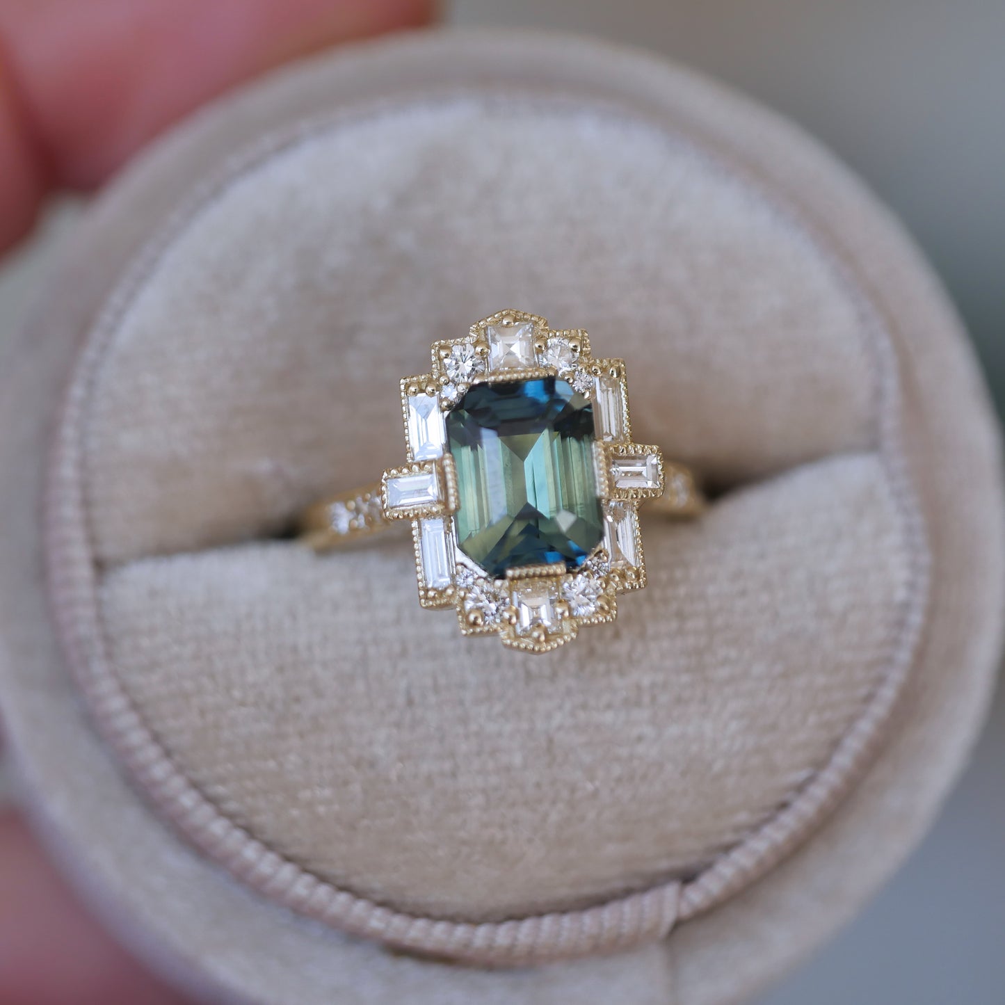 Gold ring with a green gemstone on a beige cushion