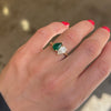 The pear-shaped emerald, symbolizing growth and renewal, beautifully complements the diamond’s brilliance, making this ring a meaningful and stunning expression of love.