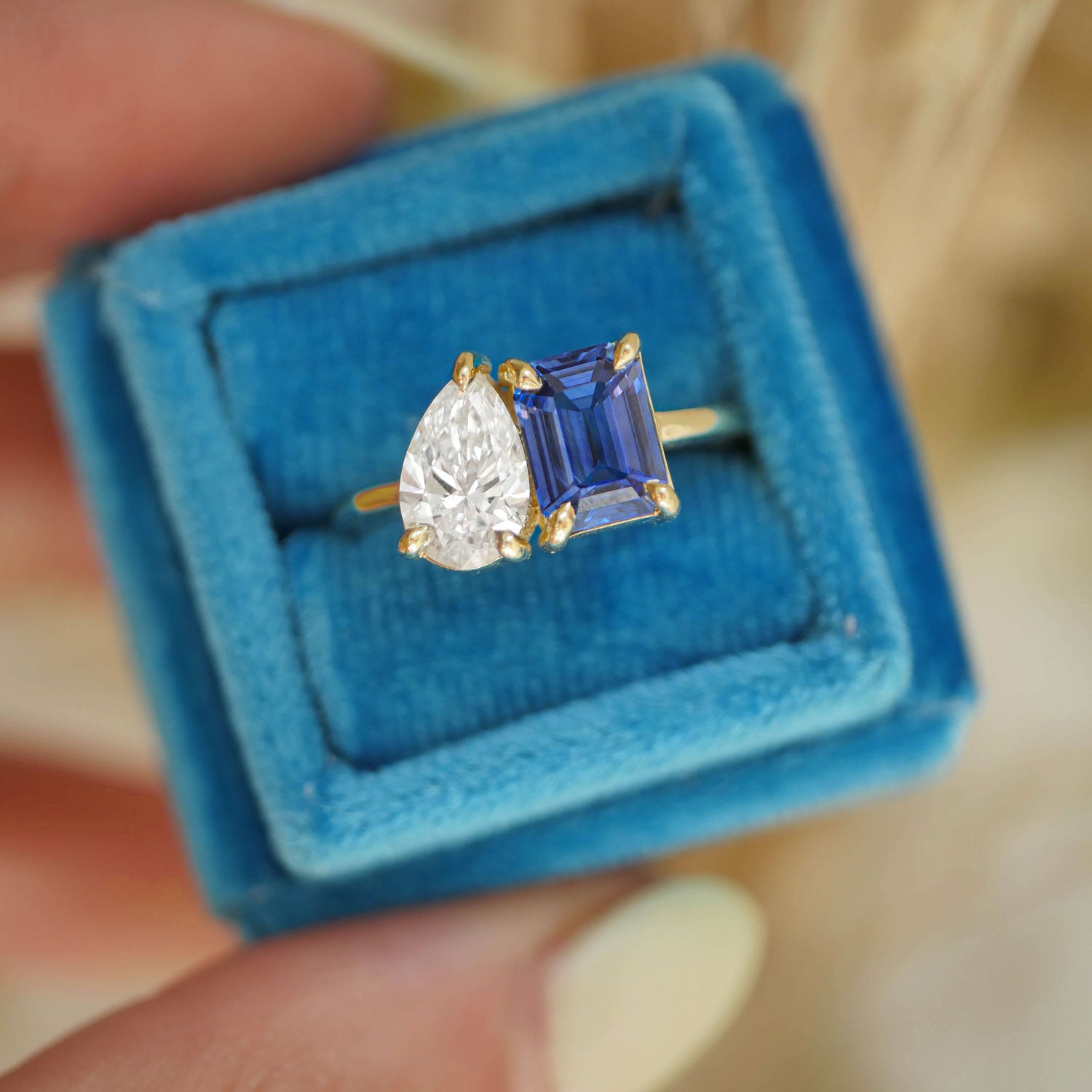 The elegant curves of the pear-shaped diamond highlight the colorful brilliance of the sapphire and emerald, making this ring a perfect representation of a love that is both dynamic and enduring.