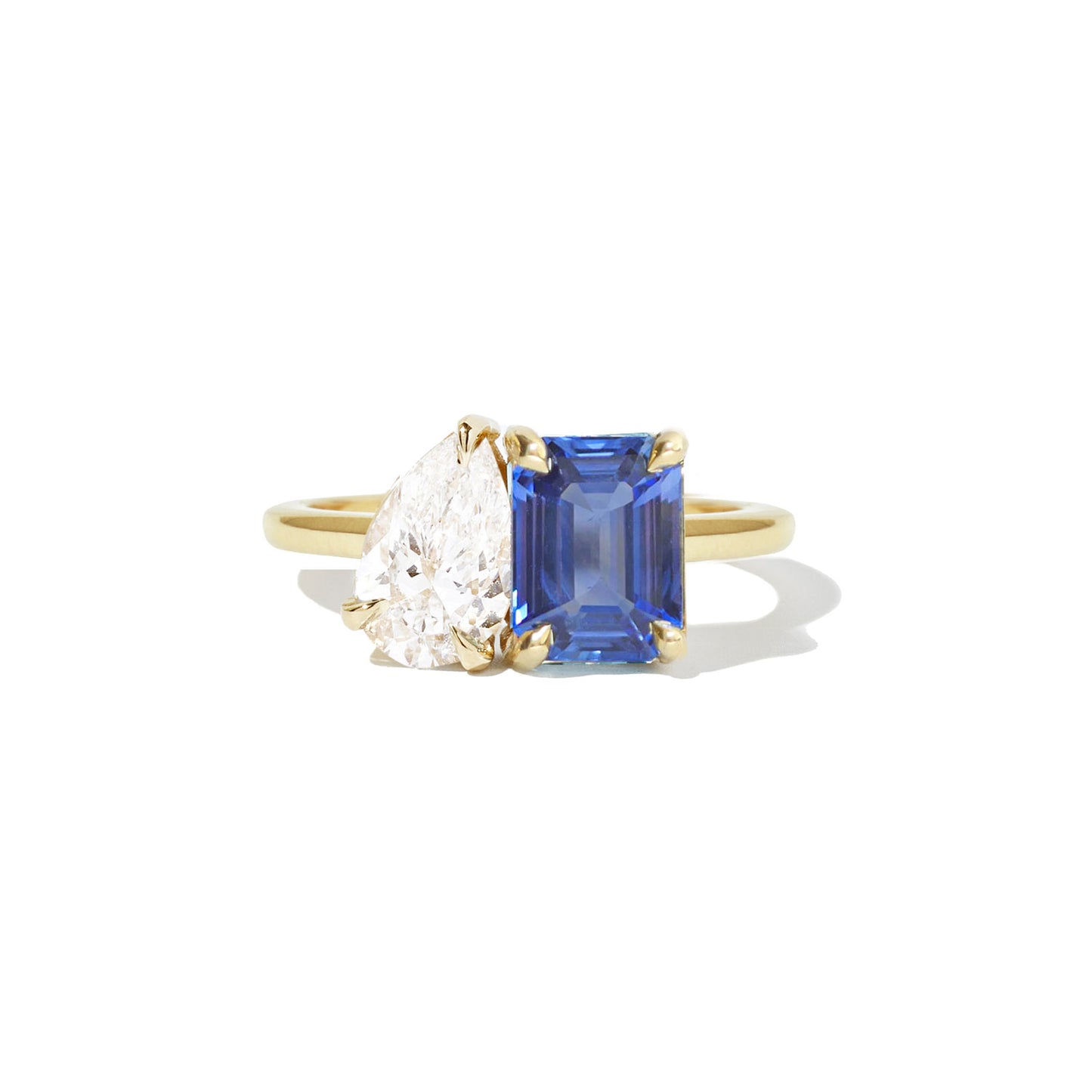 The ring elegantly combines a deep blue sapphire, a radiant green emerald, and a sparkling pear-shaped diamond, creating a truly unique and vibrant design.